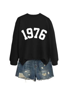 Detail of black crewneck sweatshirt with 1976 white print and distressed denim shorts