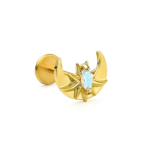 Detailed shot of golden moon and starburst cartilage piercing with opal stone inlay