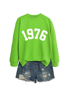 Detail view of fruit green sweatshirt with 1976 print and distressed denim shorts