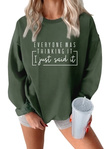 Detalle de sudadera verde oscuro de corte holgado con frase blanca y hombros caídos