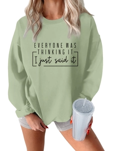 Detalle de sudadera oversize verde salvia con eslogan negro impreso para un estilo casual