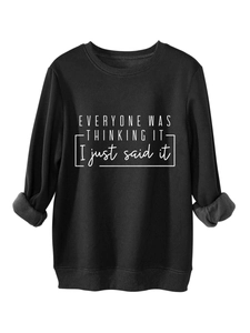 Detalle de una sudadera negra de felpa para mujer con eslogan blanco y puños rectos