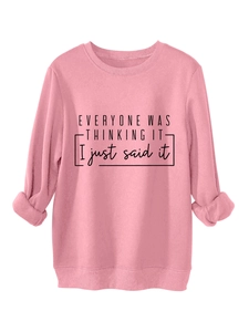 Detalle de sudadera rosa con eslogan negro y puños acanalados en tejido suave