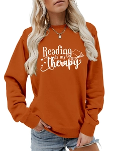 Detail of the 'Reading is my Therapy' print on a burnt orange crewneck sweatshirt