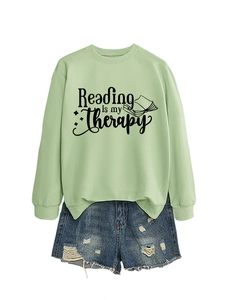 Flat lay of a light green Reading is my therapy sweatshirt with ribbed cuffs and blue denim