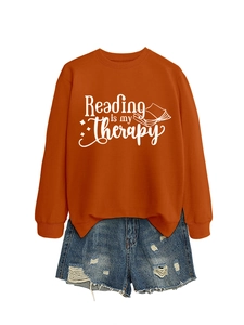 Flat lay of an orange 'Reading is my Therapy' sweatshirt with ripped blue denim shorts
