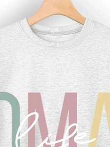 Détail d'un sweat gris avec imprimé MAMA life coloré sur un tissu en maille