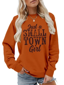 Close-up of orange sweatshirt with Just a SMALL TOWN Girl black typography print