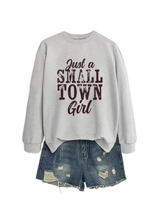 Close-up of retro 'Just a SMALL TOWN Girl' print on grey sweatshirt with denim shorts