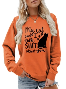 Detailed close-up of orange crewneck sweatshirt featuring funny cat silhouette and text print