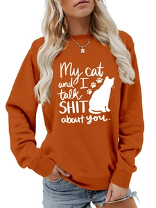 Detail of caramel orange sweatshirt featuring white cat graphics and witty slogan print