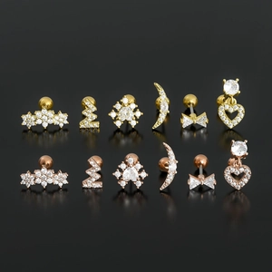 Set of 12 heart and star gold ear studs with micro-inset zircons on a black mirror background