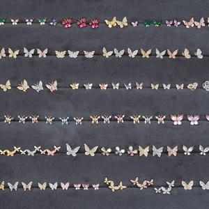 Detailed macro view of colorful zircon butterfly earrings on grey velvet tray display