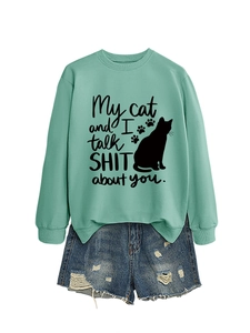 Flat lay of mint green sweatshirt with funny cat print and ripped denim shorts on white background