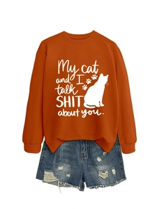 Close-up of orange sweatshirt featuring cat silhouette and funny quote with denim shorts