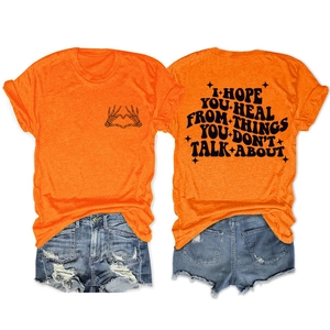 Détail du t-shirt orange avec citation au dos et motif graphique de cœur tête de mort