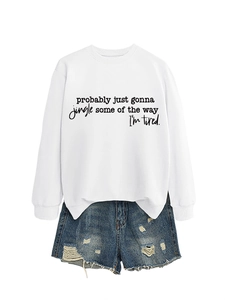 Flat lay of white slogan sweatshirt with distressed denim shorts on white backdrop