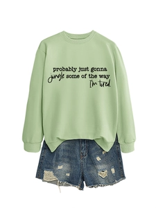 Detail of light green sweatshirt with black script text and distressed denim shorts