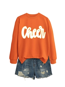 Detail von orangefarbenem Sweatshirt mit Cheer-Schriftzug und Jeans-Shorts mit Rissen