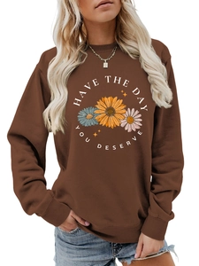 Detail of a dark brown crewneck sweatshirt with daisy flower print and positive quote text