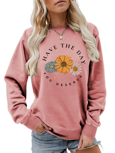 Detail of pink crewneck sweatshirt featuring floral daisy print and inspirational quote