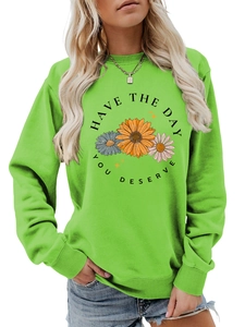 Detail of green crewneck sweatshirt featuring floral print and Have The Day You Deserve text