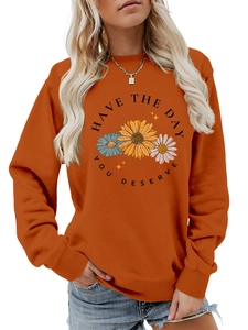 Detail view of sunflower print and Have The Day You Deserve text on orange sweatshirt