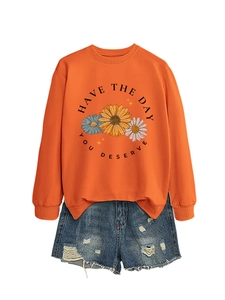 Close-up of sunflower print and 'HAVE THE DAY YOU DESERVE' text on orange sweatshirt