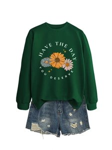 Detail of green crewneck sweatshirt with daisy print and Have The Day You Deserve text