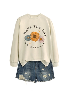 Detail of apricot crewneck sweatshirt with daisy print and distressed denim shorts outfit