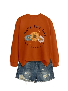 Detail of rust orange sweatshirt with daisy floral print and distressed denim shorts