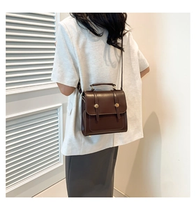 Rear view of model wearing a vintage dark brown leather backpack with gold buckles
