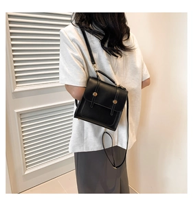 Classic black faux leather mini backpack with gold buckles shown on a model