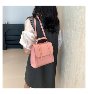 Detail of pink PU leather small square bag with golden buttons and crossbody strap