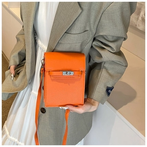 Orange crossbody phone bag with silver twist lock shown on model with grey blazer