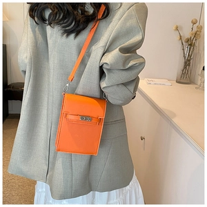 Detail of orange lychee grain leather crossbody phone bag with silver metal lock closure