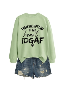 Flat lay of green sweatshirt with heart slogan and distressed denim shorts