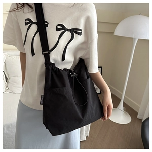 Detail view of the black nylon drawstring bag showing the side logo and wide strap