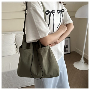 Olive green nylon drawstring bag side pocket detail shown in a cozy interior setting