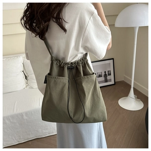 Detailed back view of an olive green nylon drawstring crossbody bag worn by a model