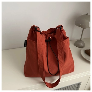 Caramel nylon drawstring tote bag on a white table with a lamp and croissant