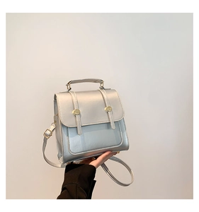 Detail of a silver PU leather backpack featuring golden metal buckles and flap design