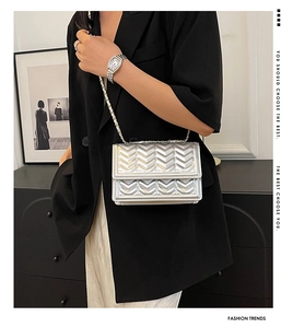 Detail of silver chevron quilted chain bag worn with black suit for elegant contrast