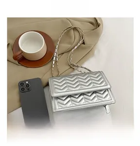Detailed view of silver quilted crossbody bag with metal chain strap and phone for size reference