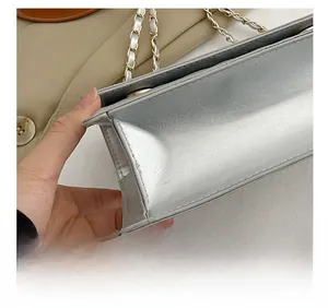 Detail shot of silver metallic leather bag with gold chain and precision stitching