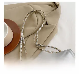 Detail of silver V-quilted shoulder bag featuring woven leather and gold chain strap