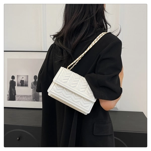 White chevron quilted bag worn by a model with a gold-tone chain strap and flap closure