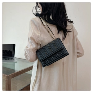 Detailed view of the V-quilted black crossbody bag with elegant metal chain strap