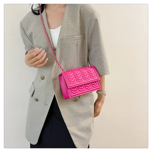 Detail of rose pink crossbody bag with V-shaped quilted texture and gold chain strap