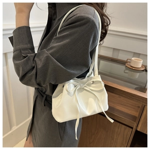 Dettaglio della borsa a secchiello in pelle bianca con grande fiocco e texture arricciata